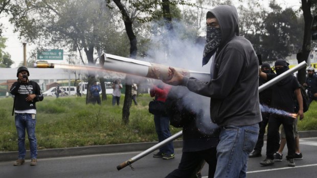 Makeshift weapons: Demonstrators fire fireworks towards riot police during a protest over the missing Ayotzinapa students, near the Benito Juarez International airport in Mexico City.