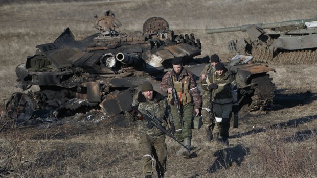 Russia-backed separatists walk after inspecting destroyed Ukrainian army tanks for functional weapons and ammunition near the village of Lohvynove.