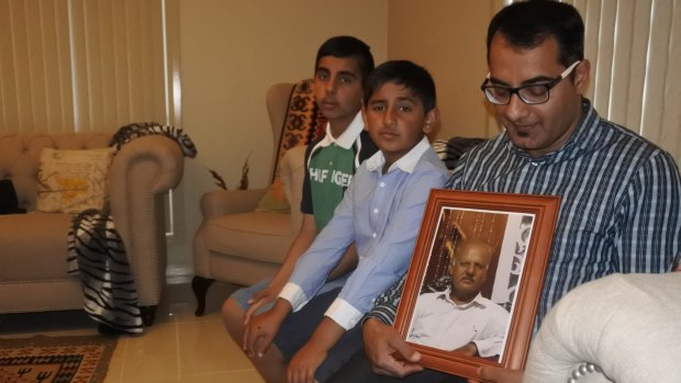 Kamran Ahmed, with sons Khakan and Sultan, holds a photo of his first cousin Sheikh Sajid Mehmood, who was killed in Pakistan on November 27.