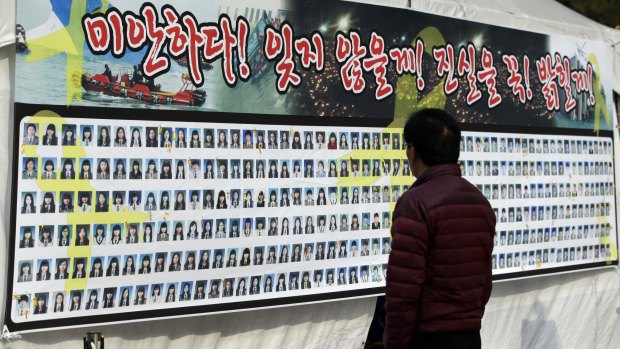 A man looks at portraits of the Sewol ferry disaster's victims on a poster in Seoul on Tuesday. The government has called off the search for nine bodies still missing, citing winter conditions.