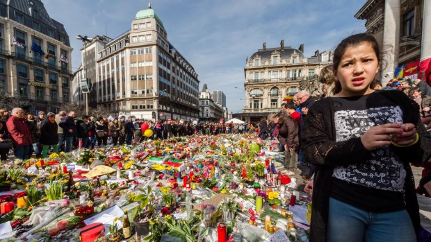People stop and look at floral tributes at a memorial site at the Place de la Bourse in Brussels, days after the attack.