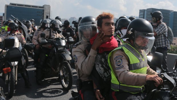 Bolivarian National Police officers ride away on a motorcycle with a detained anti-government protester, in Caracas.