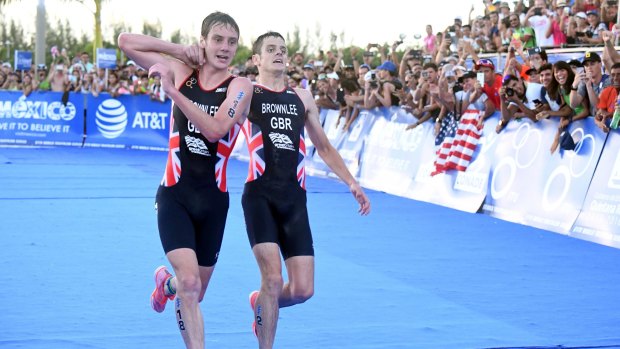 Britain's Alistair Brownlee, left, helps his brother Jonny to get to the finish line during the Triathlon World Series event in Cozumel, Mexico.
