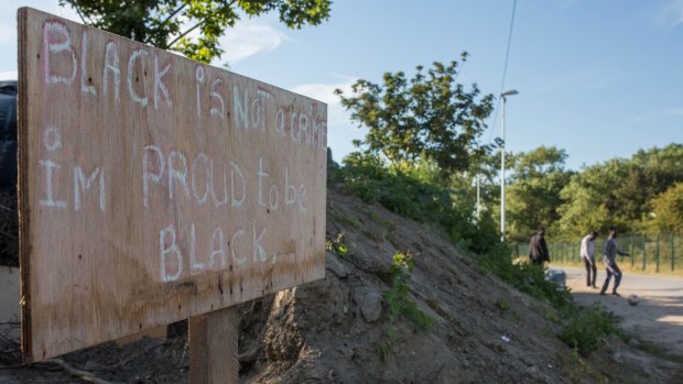 A sign reading "Black is not a crime, I'm proud to be black" by a track behind a camp in Calais.  