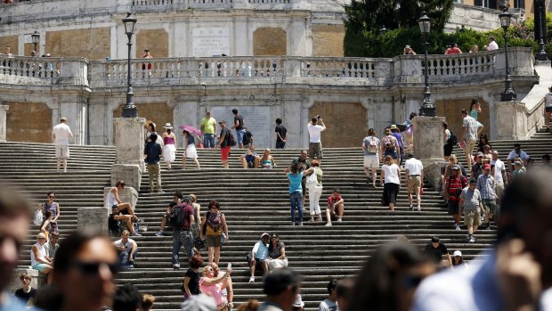 Pedestrians walk past the Spanish Steps in Rome.