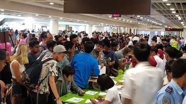 Crowds of passengers cram customer service desks set up at Denpasar airport's international terminal on Monday.