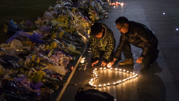 Mourners light candles at a makeshift memorial at the site of a stampede in Shanghai that left at least 36 people dead.