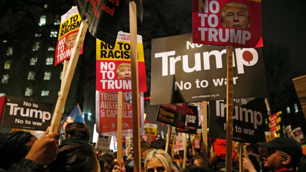 Demonstrators hold banners as they take part in a protest against US President Donald Trump outside Downing Street in London.