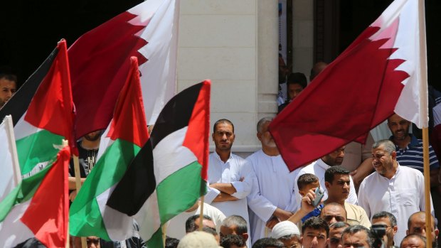 Residents of a Qatari-funded housing complex wave their national and Qatari flags during a demonstration in solidarity with Qatar in Khan Younis, Gaza Strip, last month.