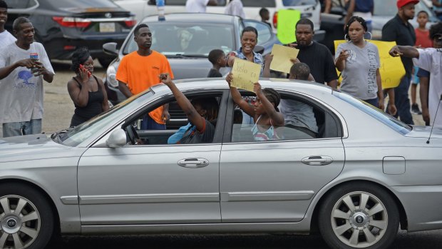 People gather in protest outside of the Triple S Food Mart.