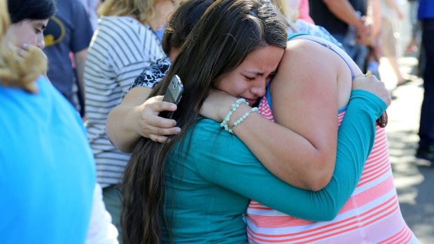 Grim toll: A woman is comforted after the shooting at Umpqua Community College.