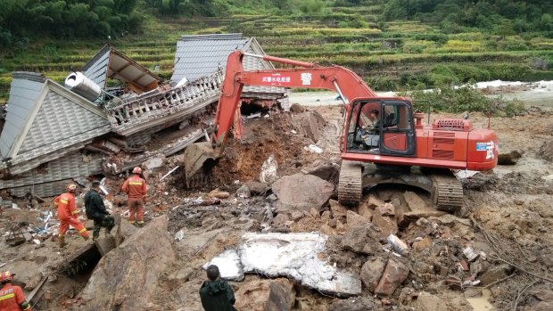Rescuers use heavy equipment to dig in the rubble of a house that was destroyed in a landslide in Sucun village, China, on Thursday.