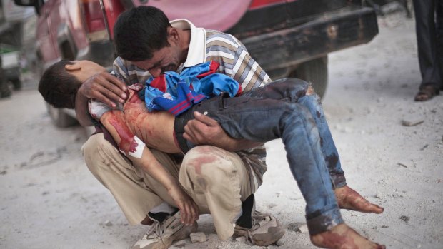 A man holds the lifeless body of his son near Dar al-Shifa hospital in Aleppo in October 2013.