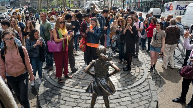 Tourists gather around the sculptures "Charging Bull" and "Fearless Girl".