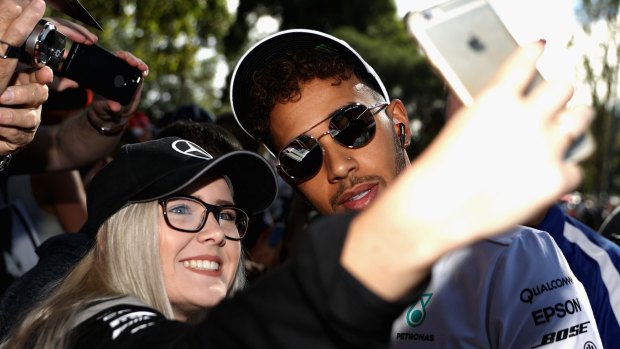 Lewis Hamilton arrives at the circuit and poses for a photo with fans.