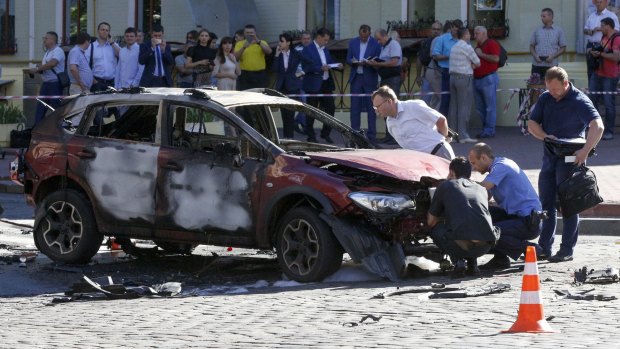 Forensic experts examine the wreckage of a burned car in Kiev, Ukraine.