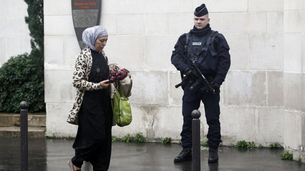 A French police officer stands as a Muslim woman leaves the Great Mosque of Paris after the Friday prayers on November 20, 2015 in Paris.