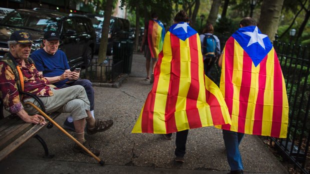 Two men watch pro-independence supporters passing by  outside the United Nations headquarters in New York on Wednesday.