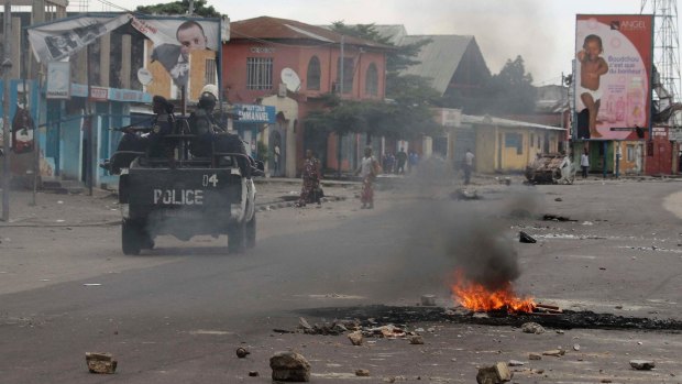 Policemen drive past burning debris during protests against President Joseph Kabila in Kinshasa on Tuesday.