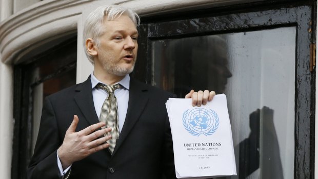 Julian Assange, standing on the balcony of the Ecuadorian embassy in London, holds the UN report saying he has been "arbitrarily detained" by Britain and Sweden since December 2010.