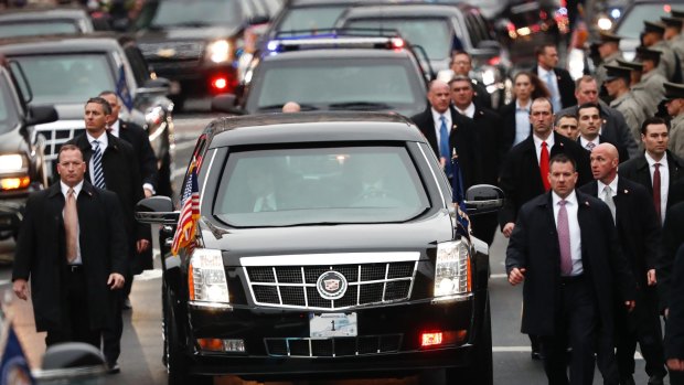 Donald Trump's motorcade is protected by Secret Service agents as it moves along the Inauguration Day parade route.