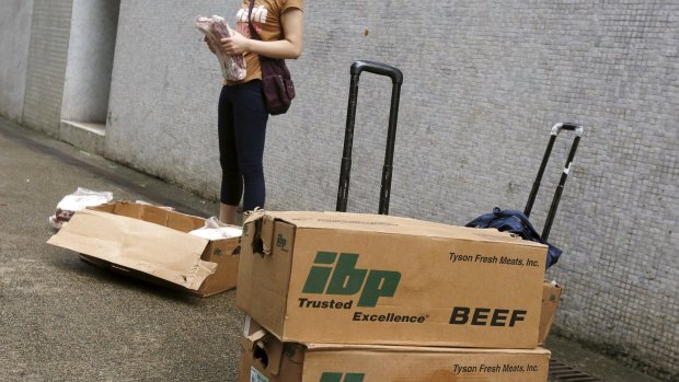 A woman holds unpacked frozen beef ribs from the US along a back alley at an industrial area in Hong Kong, before the meat is hand-carried and smuggled across the border into mainland China.