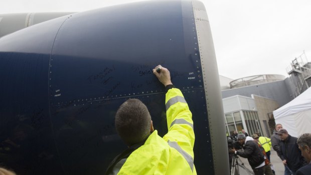 An attendee signs the engine of the Delta 747-400 at Paine Field in Everett.