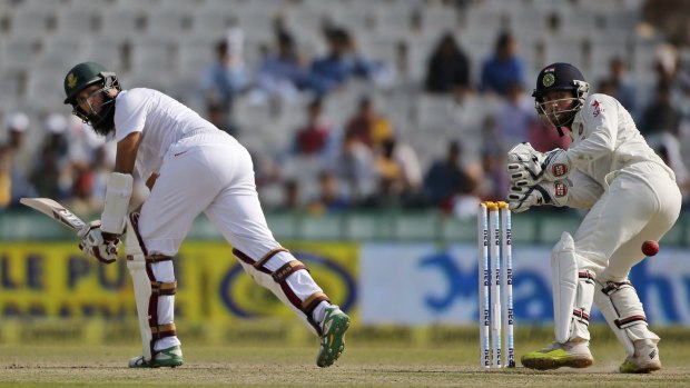 South Africa's captain Hashim Amla glances a delivery down the legside as wicketkeeper Wriddhiman Saha looks on.