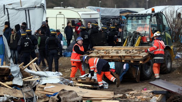Workers and police officers clear part of the Jungle after a French court confirmed an eviction order.