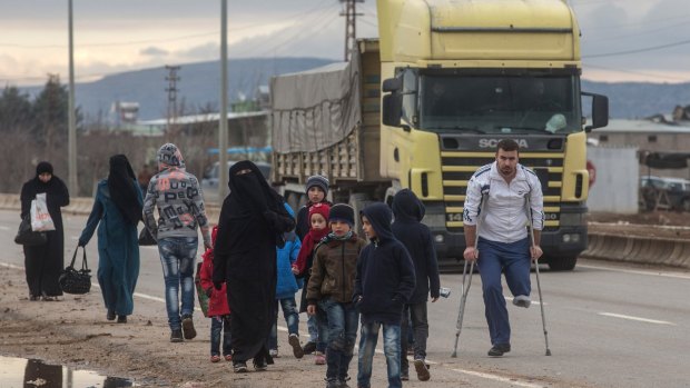 A truck arriving at the border passes people walking towards a temporary housing complex at the closed Turkish border gate in Kilis on Sunday.