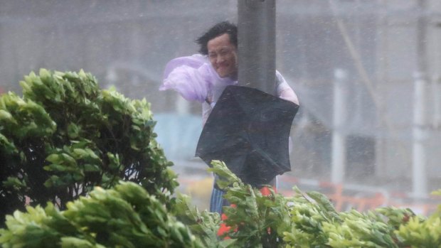 A man holds onto a lamp post against strong wind as Typhoon Hato hits Hong Kong on Wednesday.