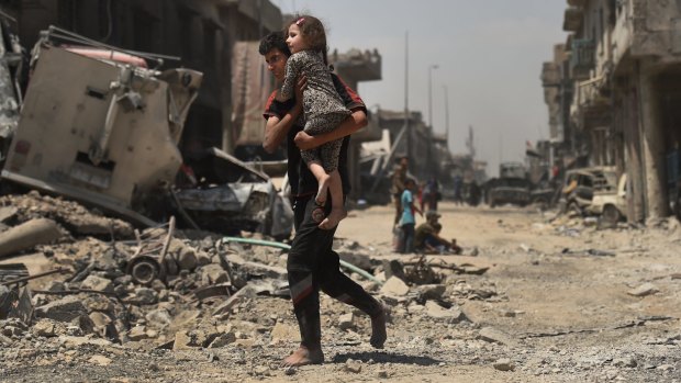 An Iraqi male runs barefoot carrying his sister as they escape from  the front lines in West Mosul a week ago.