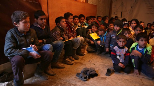 Syrian refugee children sit on the ground inside a makeshift school at a Syrian refugee camp in Qab Elias, Lebanon. 