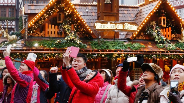 Chinese tourists take pictures of the Christmas market in Frankfurt. Chinese tourists are the world's highest overseas spenders. 