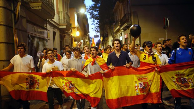 Anti-Catalan independence demonstrators carry a Spanish flag as they march in Barcelona on Tuesday.