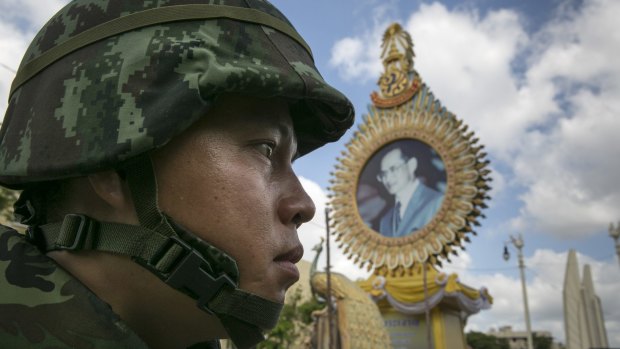 A Thai soldier patrols near government buildings in front of a portrait of King Bhumibol Adulyadej in May.