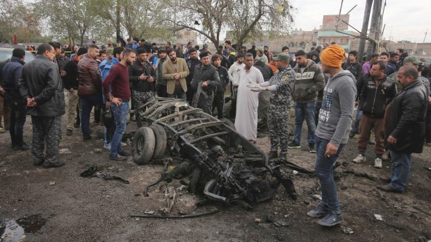 Security forces inspect the scene after a car bomb killed dozens at a crowded outdoor market in Baghdad on Monday.