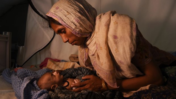 Laila Begum holds her son Ifran's hand as he receives treatment in a Red Cross hospital tent at a Rohingya refugee camp in Bangladesh.
