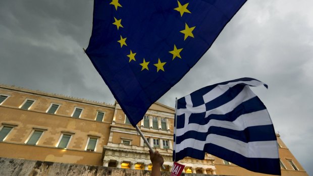 Protesters wave Greek and EU flags during a pro-Euro rally in front of the parliament building, in Athens on Tuesday.