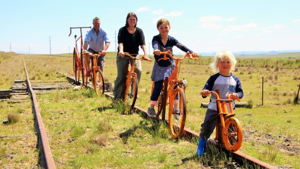 Will Jardine and his wife Caroline and two children Izzy, 6, and Jack, 3, pose on bikes on the old railway line between Cooma and Nimmitabel.