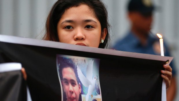 A protester displays a portrait of slain Kian Loyd delos Santos, a 17-year-old grade 11 student, who was killed by Philippine police last.