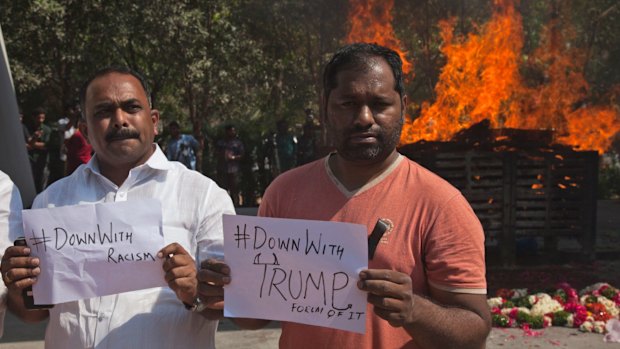 Indians hold placards in front of the cremation pyre of Srinivas Kuchibhotla in Hyderabad, India.