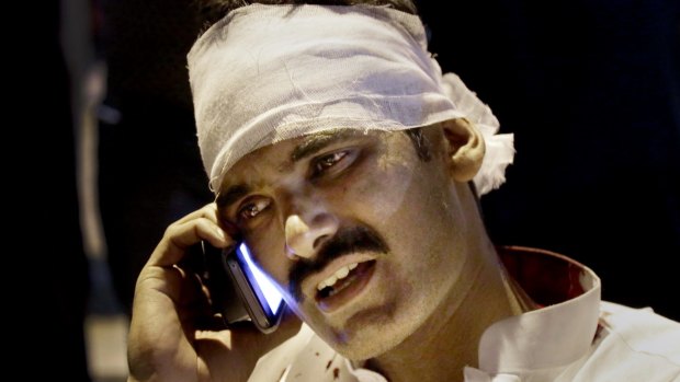A man injured by the bomb blast talks on his  phone at a local hospital in Lahore on Sunday. 