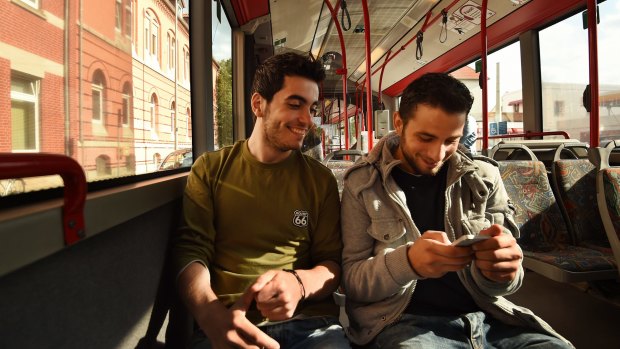 Ali Deeb (left) with his friend Ahmed (right) recieve messages from fellow refugees who fled Libya, on a bus in the German town of Braunschweig.