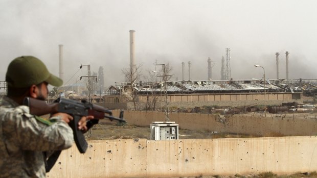 An Iraqi Shiite militiaman searches the Baiji oil refinery, until recently held by militants of the Islamic State group.