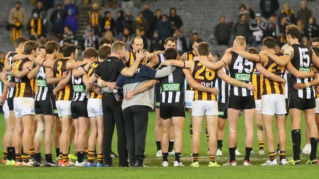 The huddle that ushered in the weekend - Collingwood and Hawthorn players link arms in tribute to Phil Walsh.