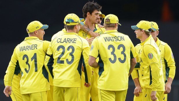 Mitchell Starc is surrounded by his teammates after taking the wicket of Calum MacLeod of Scotland.
