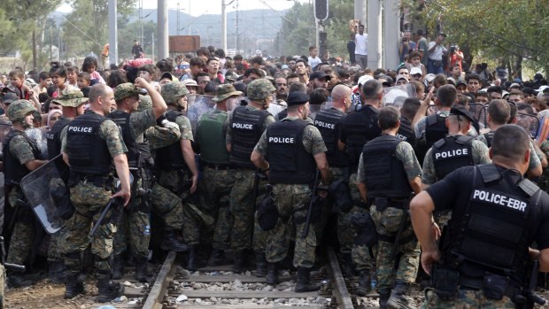 Macedonian police block migrants from entering Macedonia from Greece.