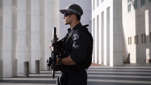 An AFP officer stands guard at the front of Parliament House in Canberra. 