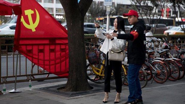 A 'deputised citizen' gives direction to a resident near a Chinese Community Party flag on the streets of Beijing on Monday amid extraordinary security measures.